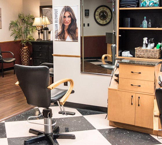 Hair stylist's workplace with adjustable chair, wall mirror, and a shelving unit filled with products and tools